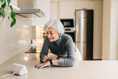 Woman smiling happily while using smart devices in her kitchen.