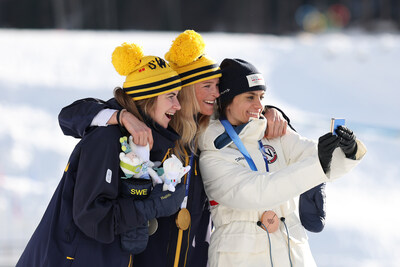 (Above) VAL DI FIEMME, ITALY - FEBRUARY 07: Gold medalist Frida Karlsson of Team Sweden (C), Silver medalist Ebba Andersson of Team Sweden (L) and Bronze medalist Heidi Weng of Team Norway celebrate by taking a victory selfie during the medal ceremony for the Women's 10km + 10km Skiathlon on day one of the Milano Cortina 2026 Winter Olympic games at Tesero Cross-Country Skiing Stadium on February 07, 2026 in Val di Fiemme, Italy. (Photo by Maddie Meyer/Getty Images)